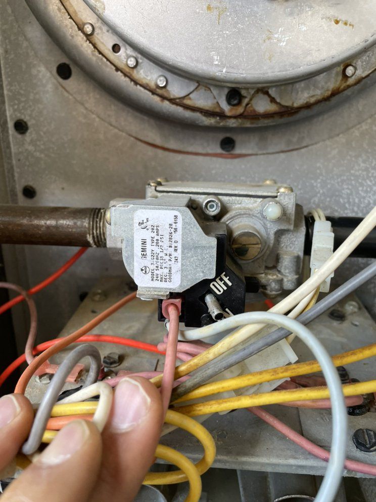 A Temperature Select Air technician works on a furnace gas valve and burner wiring during a heating repair.