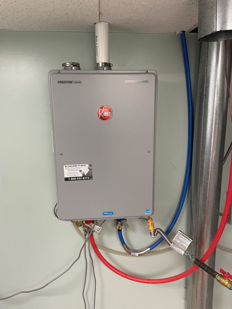 A Rheem Prestige tankless water heater installed with neat piping connections by Temperature Select Air.