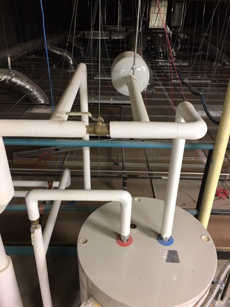 A commercial water heater and insulated piping installed above a ceiling by Temperature Select Air.